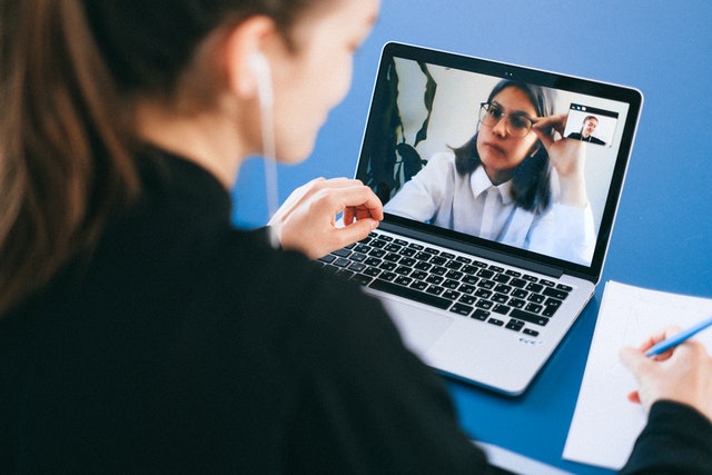Zwei Personen besprechen per Videokonferenz auf einem Laptop ein zu lösendes Problem